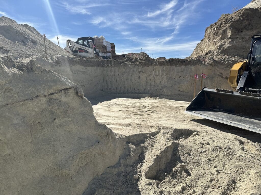 Construction excavation with white and yellow loaders.
